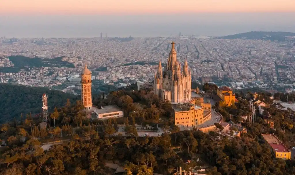 Vista del Tibidabo con su templo en primer plano, y la ciudad de Barcelona extendiéndose al fondo bajo un cielo despejado