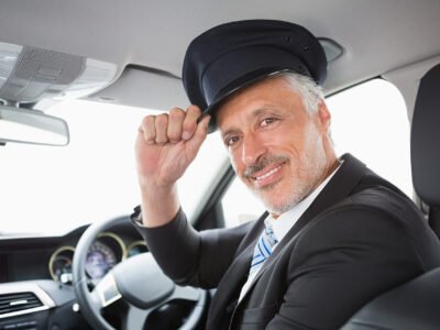 Conductor profesional de LimoluxBCN saludando desde una limusina. Servicio de chófer privado y limusinas en Barcelona