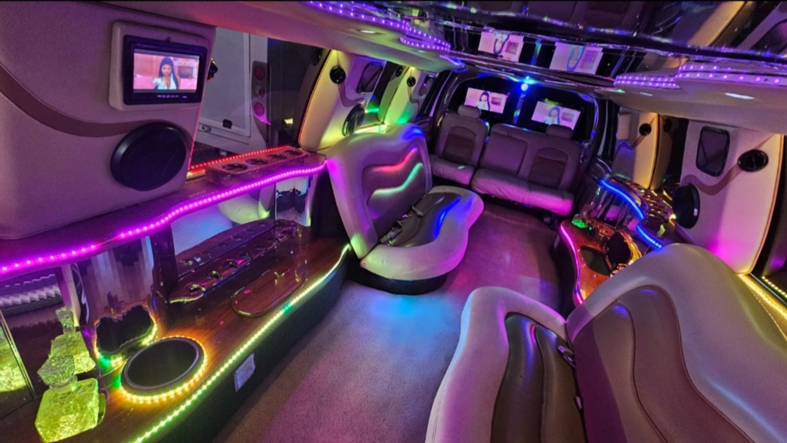 Interior de la limusina con tiras LED rojas en techo y paredes, mostrando un ambiente de estilo lounge.