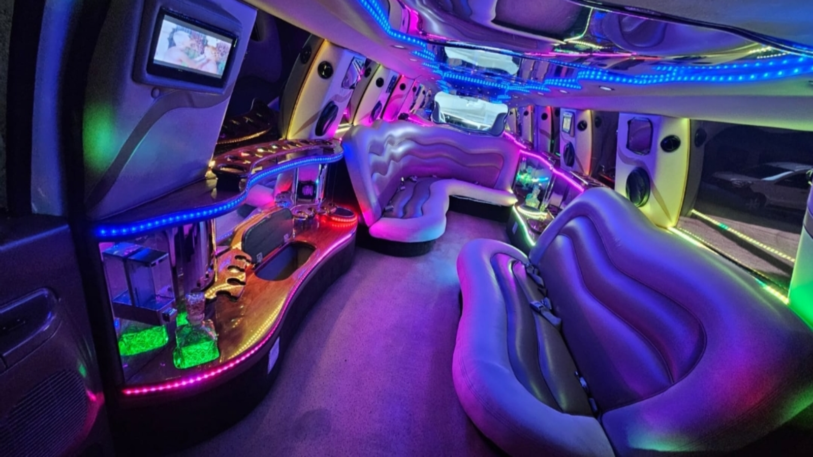 Interior de la limusina con asientos de lujo e iluminación LED azul a lo largo del techo y los laterales.