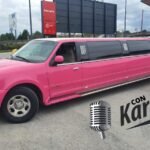 Limusina Barbie Navigator rosa de 12 plazas aparcada en una calle de Barcelona, con la ciudad de fondo.