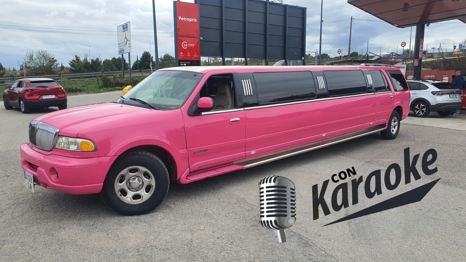 Limusina Barbie Navigator rosa de 12 plazas aparcada en una calle de Barcelona, con la ciudad de fondo.