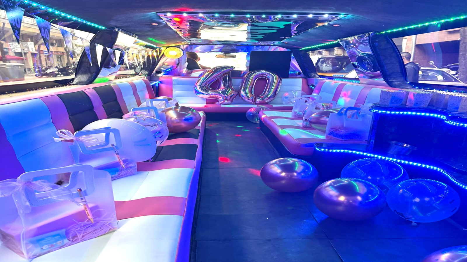 Interior de la limusina Barbie rosa decorada para un cumpleaños de 40 años, con luces y ambiente festivo.