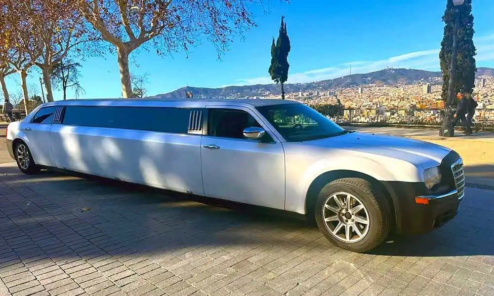 Limusina Chrysler blanca estacionada en una masía durante una celebración de boda.