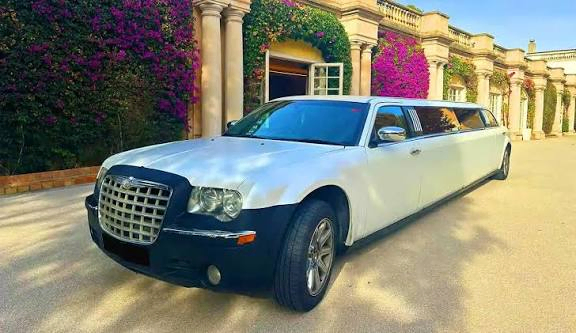 Limusina Chrysler blanca estacionada en una masía durante una celebración de boda.