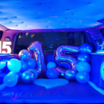 Interior de una limusina Hummer rosa, decorada para un cumpleaños, con asientos de cuero, iluminación LED de colores y adornos festivos que crean un ambiente de celebración.